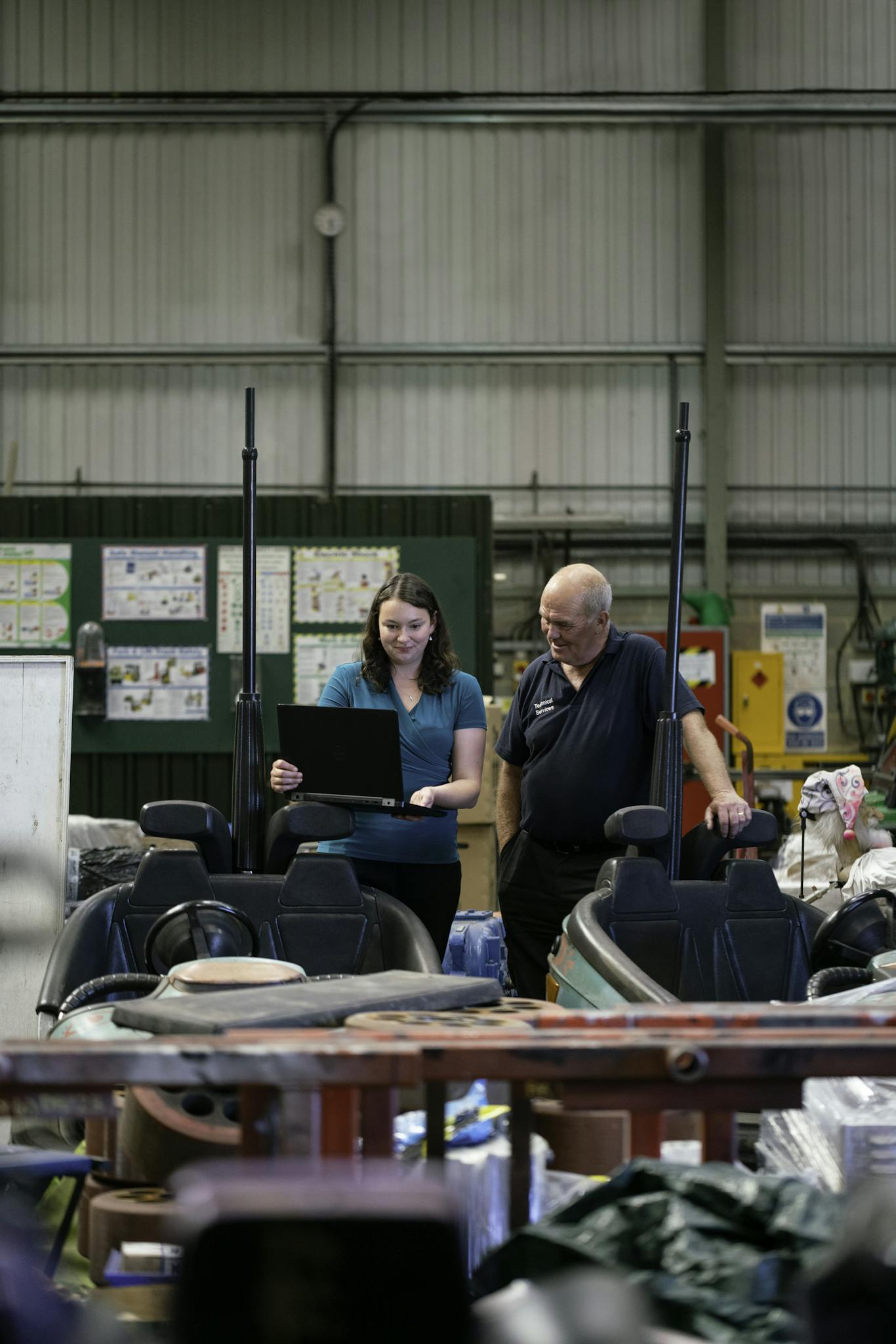Two technicians discussing bumper car maintenance in a workshop.